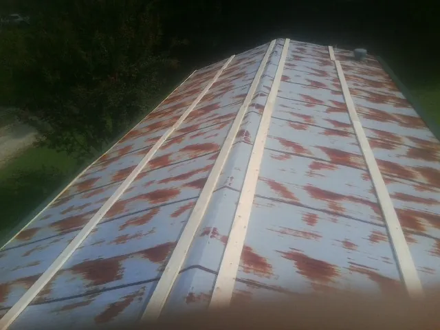 Rusted metal roof panels with new wood purlins before replacement — Storm Damage Roof Repair in Twin Lake by Roofing Brothers