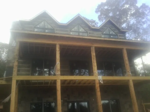 Dormers and porch framing on a large log home under construction — Roof Coating work by our crew in Twin Lake