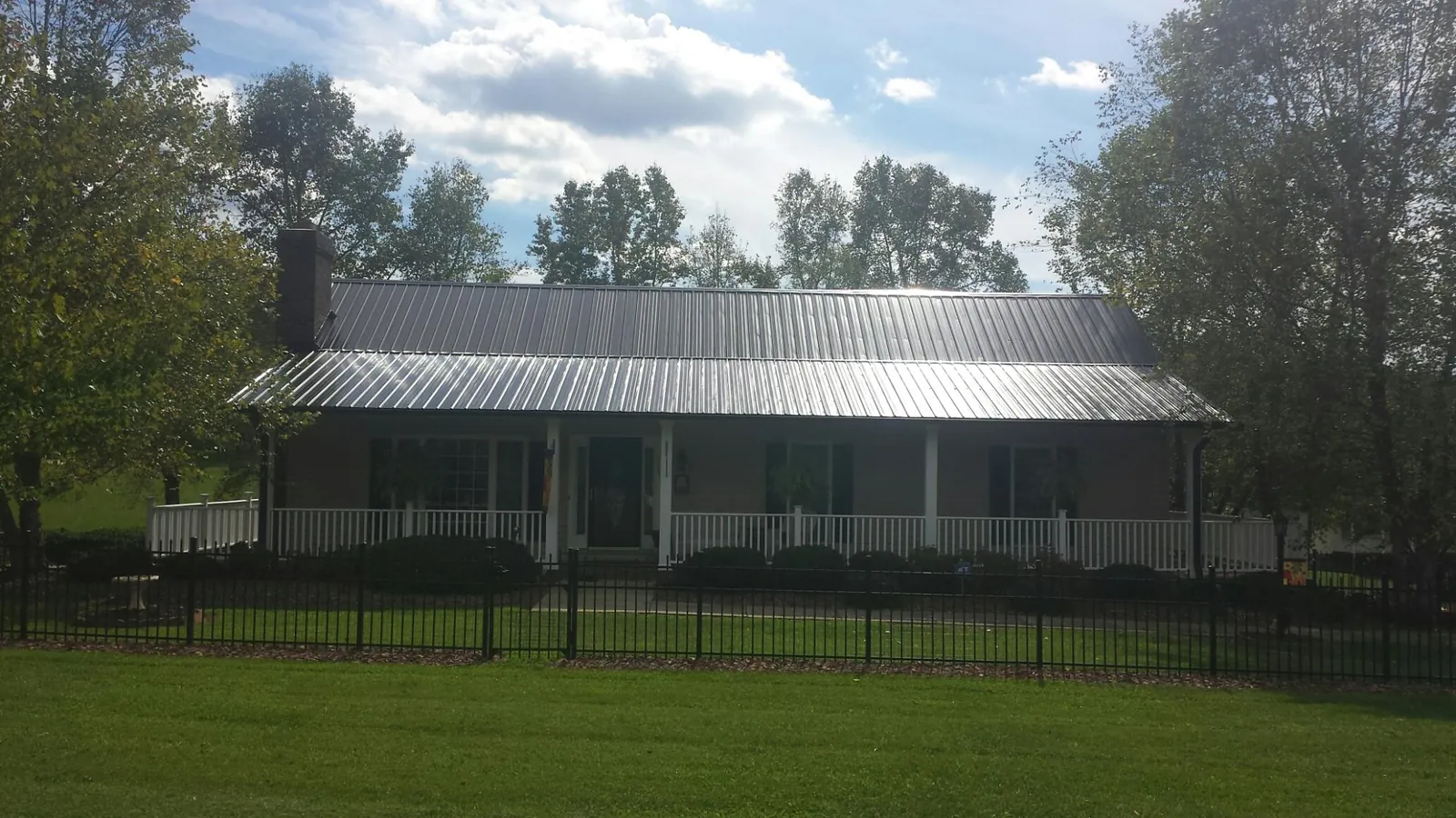 Gray metal roof on a brick ranch with a full width front porch — Gutter Guard Installation work by our crew in Twin Lake