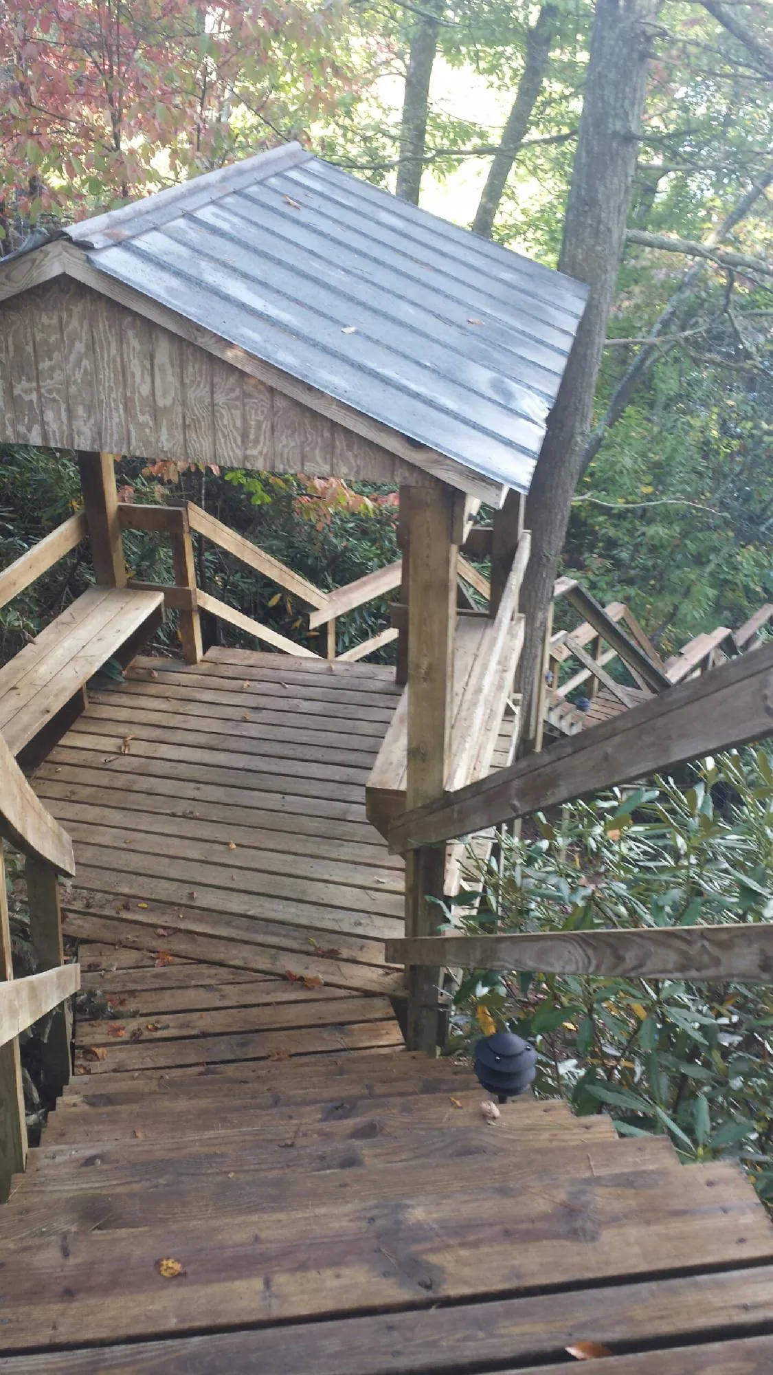 Metal roofed shelter over wooden steps on a wooded walkway — Skylight Repair & Installation work by our crew in Twin Lake
