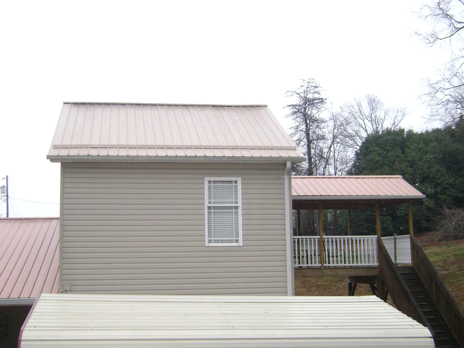 Tan metal roofs on a two story addition and attached porch, from a Roof Replacement job in Twin Lake