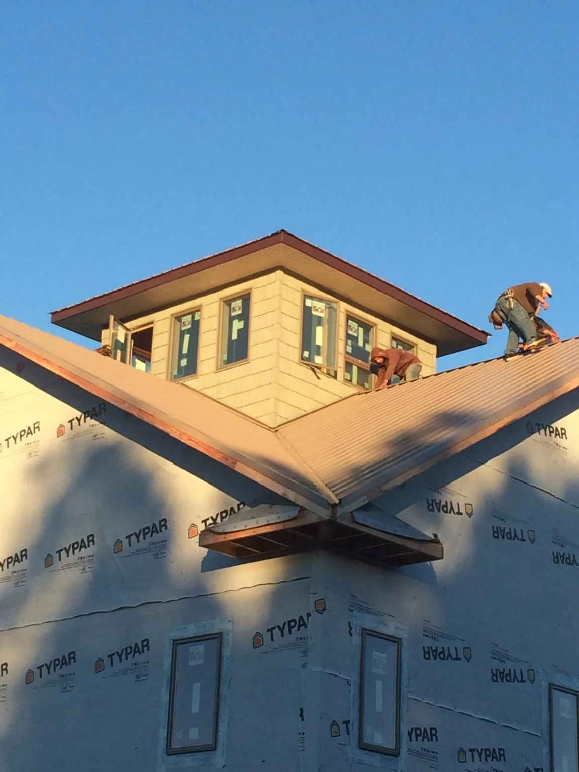 Roofers working around a rooftop cupola on a new metal roof at sunset — Roof Waterproofing in Twin Lake by Roofing Brothers